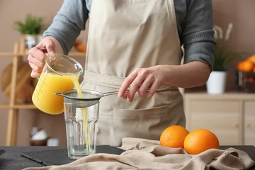 Schilderijen op glas Woman preparing orange juice in kitchen © Pixel-Shot