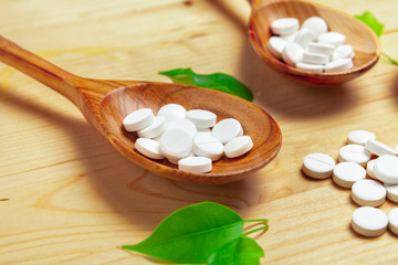 Medicine capsules, pills on wooden spoon background