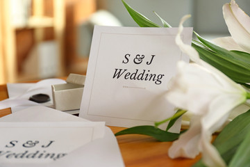 Wedding invitations and flowers on table in room