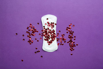 Menstrual pad with red sequins on color background. Menstruation concept © Pixel-Shot