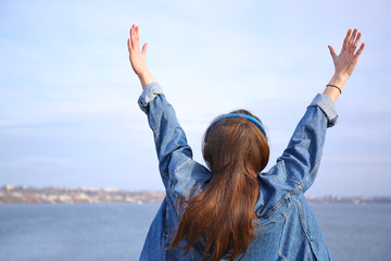Young woman listening to music near river