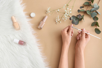 Woman doing manicure on color background