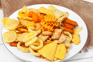 Mix of snacks : pretzels , crackers , chips  and nachos on the table