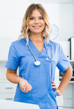Friendly girl in doctor's uniform smiling at office