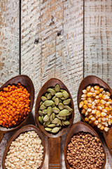 Various colorful grains and seeds in wooden spoons - close up
