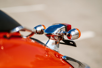 Closeup chrome detail and taillight and turn signals of orange retro vintage scooter.