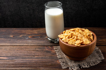 Corn flakes on dark wooden background.