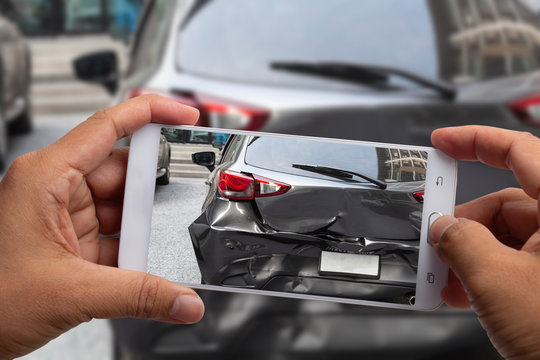 Car insurance agents take pictures of accident-damaged with smartphone for insurance claim.