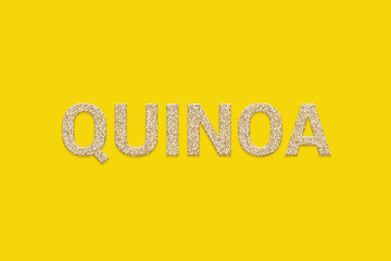 White Quinoa grains texture text on yellow color background. White Peruvian Incan super food seeds. Typography of Whole grain raw organic quinoa seeds. Vegan detox food.