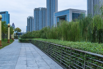 Fototapeta premium park pedestrian walkway and modern skyscrapers, dalian city, china.