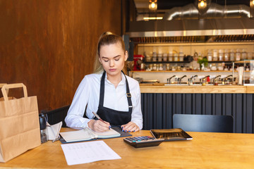 Young woman doing finance calculating bills and expenses of small business 