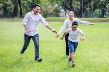 happy asian Family, parents and their children running around  in park together. father mother and son having fun and laughing outdoors . cheerful