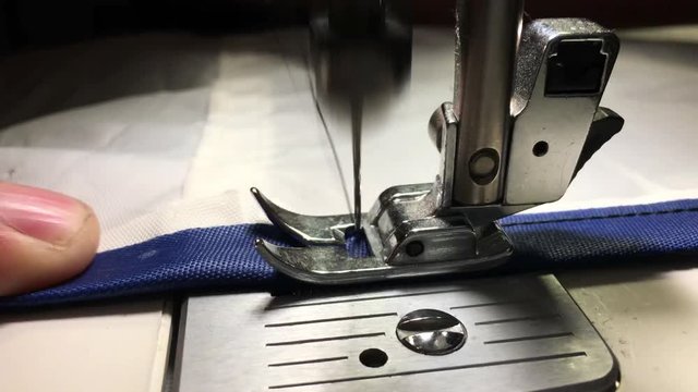 Worker stitches cloth on the sewing machine. Cratches the thread on the fabric.