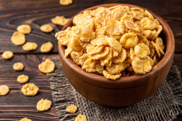 Corn flakes on dark wooden background.