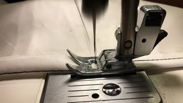Worker stitches cloth on the sewing machine. Cratches the thread on the fabric.