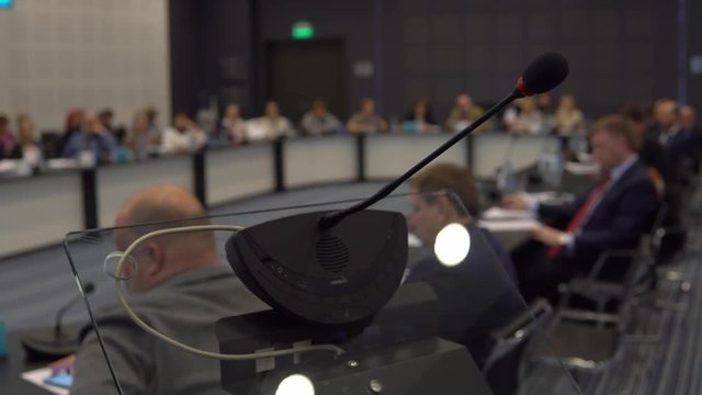 Close-up. Conference microphone for speakers against the background of people in the conference hall. Movement down