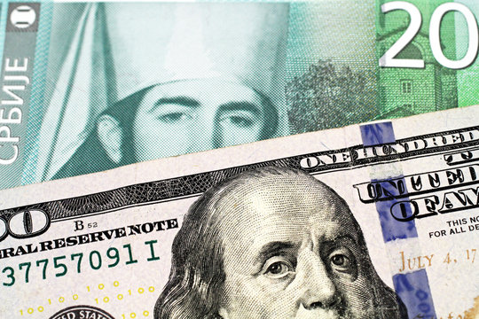 A close up image of an American one hundred dollar bill with a twenty dinar bank note from Serbia in macro