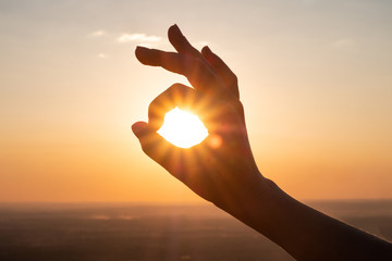 Fototapeta na wymiar hand sign and sun rays going through hands at sunset