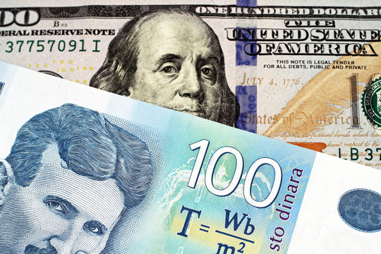 A close up image of a blue one hundred Serbian dinar bank note with an American one hundred dollar bill in macro