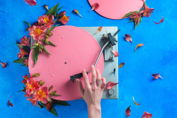 Colorful vinyl record player with petals and leaves. Pink pop up conceptual flat lay with flowers. Spring music still life