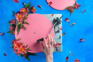 Colorful vinyl record player with petals and leaves. Pink pop up conceptual flat lay with flowers....