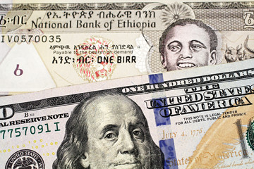 A close up image of a grey one Ethiopian birr bank note in macro with a one hundred American dollar bill 