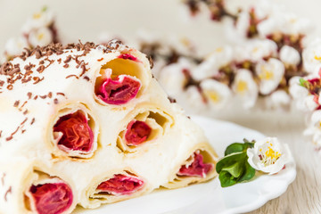 Dessert cake cherry slide and flowering branches of apricot. On wooden background