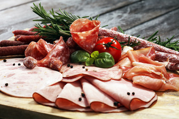 Food tray with delicious salami, pieces of sliced ham, sausage and salad. Meat platter selection.