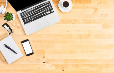 Modern laptop computer. Top view of wooden office desk with laptop computer, smartphone, notebook, headphone, plant and cup of coffee. Modern office. Copy space for text.