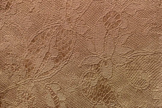 Texture of fragment genuine leather with an abstract floral ornament close-up. Vintage golden bronze color. For background , backdrop