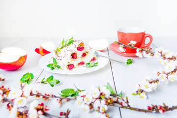 Dessert cake cherry slide, a cup of black tea and flowering branches of apricot. On wooden background