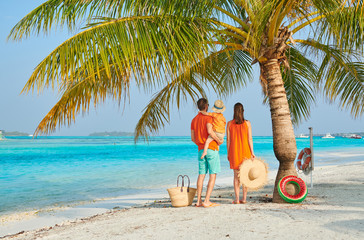 Family of three on beach under palm tree