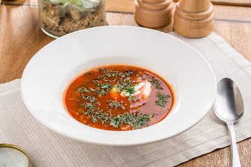 Red beetroot soup borshch with beef and sour cream on wooden table