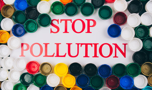 Plastic pollution concept. Refuse single-use plastic. Words Stop Pollution in the center of colored background of different plastic lids, top view. Single-use plastics, EU European directive to help