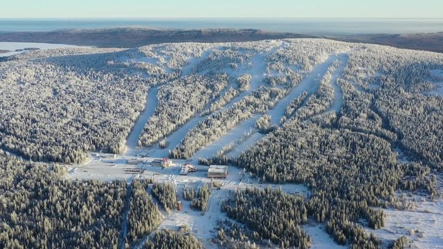 Aerial view of ski resort surrounded by forest in winter. Footage. Outdoor sports