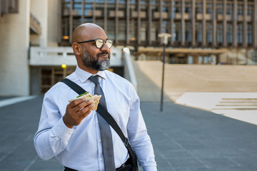 Businessman eating take away sandwich outdoor