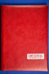 Red folder with the words Confidential for internal use only, on a blue velvet background. General...