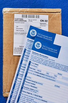 Customs Declaration Forms lies on Parcel with Customs declaration form CN22 on a blue velvet background. General view.