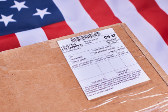 Parcel with Customs declaration form CN22 on American flag background. Close-up