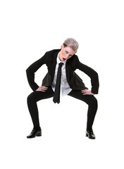 Cool looking modern alternative woman wearing a trouser suit, shirt and tie. She is crouching with attitude, looking to the camera, photographed isolated on a white background.