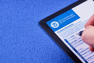 Human fills Form of the customs declaration on a blue velvet background. Close-up - obrazy, fototapety, plakaty