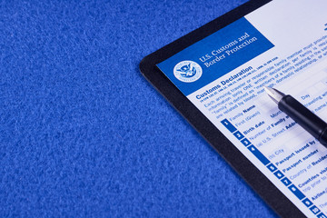 Form of the customs declaration and pen on a blue velvet background. Close-up