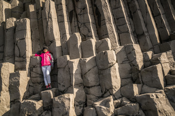 Traveler travel to unique volcanic rock formation on Iceland black sand beach located near the village of Vik i myrdalin South Iceland. Hexagonal columnar rocks attract tourist who visit Iceland.