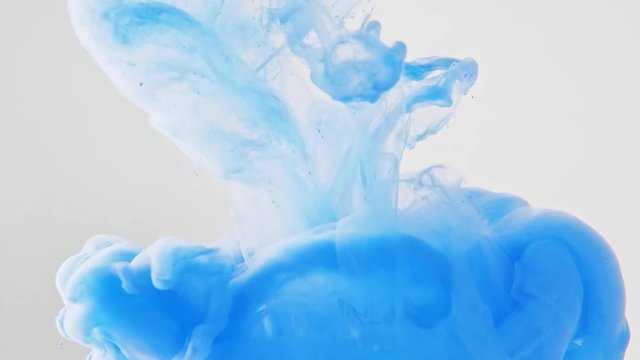 Blue ink dropped into water, close shot. Abstract background. Acrylic swirl in liquid. Drop of paint dissolving into water. Abstract pattern. Blue paint disapearing in liquid. Blurred background