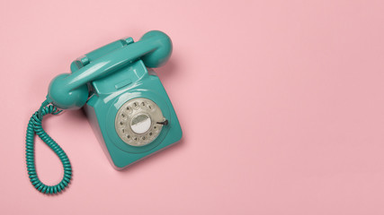 Blue vintage phone on a pink background with copy space
