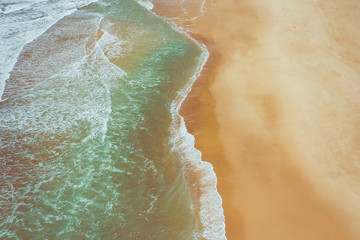 Aerial view to ocean waves. Yellow sand beach. Blue water background. Photo made from above by drone.