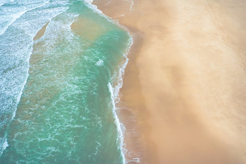 Fototapeta na wymiar Aerial view to ocean waves. Yellow sand beach. Blue water background. Photo made from above by drone.