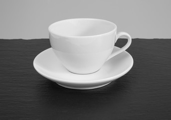 White mug and saucer on a wooden table.