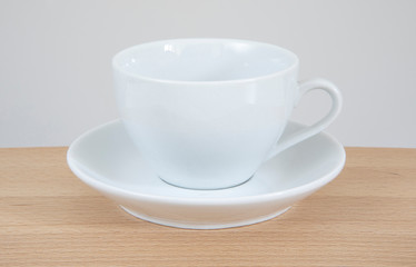 Obraz na płótnie Canvas White mug and saucer on a wooden table.