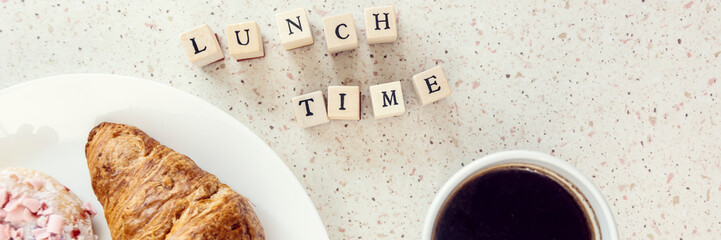 plate of baked sweets cup of coffee and lunch time letters on wooden bloks panorama